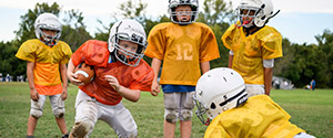Children wearing protective equipment, playing American tackle football