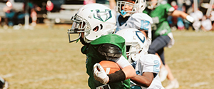 Children wearing protective equipment, playing American tackle football